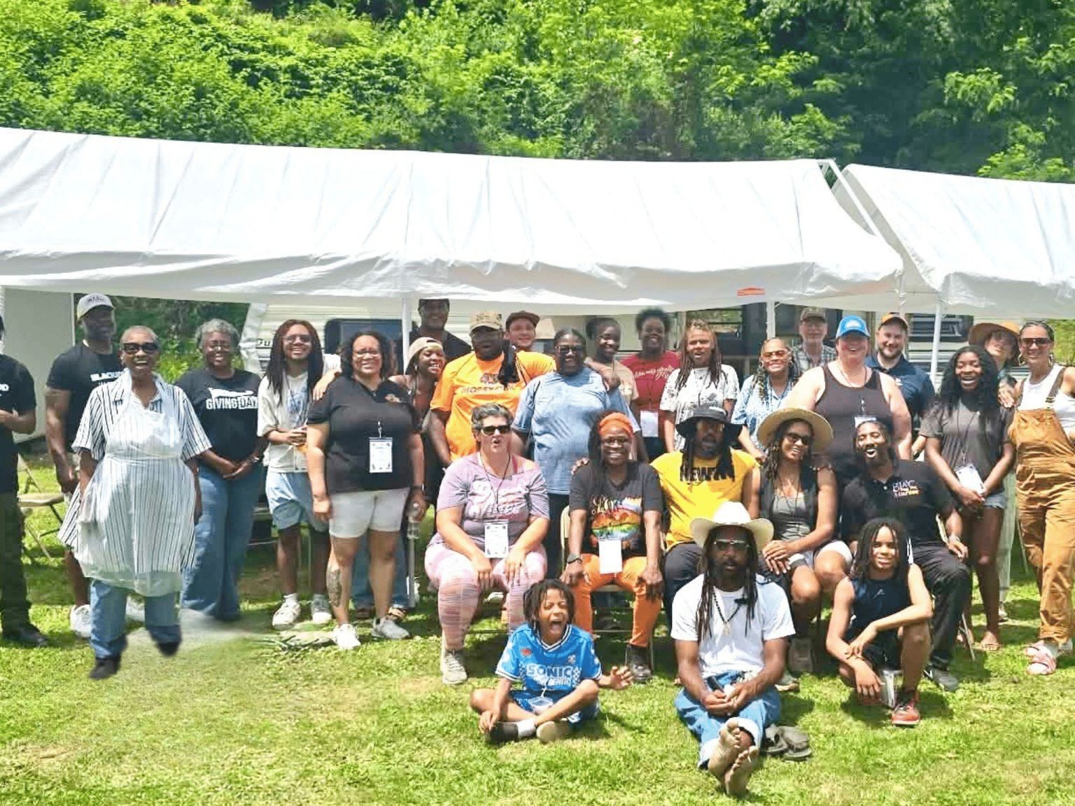 A large group of visitors, families and farmers gathered on the grass in front of white tents at T&T Organics.