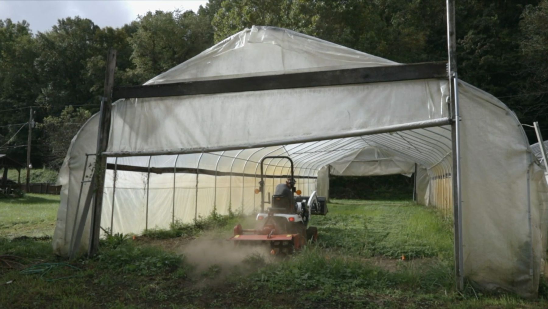 A tractor tilling ground inside a T&T high tunnel.